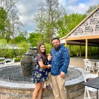 a man and woman posing in front of a fountain